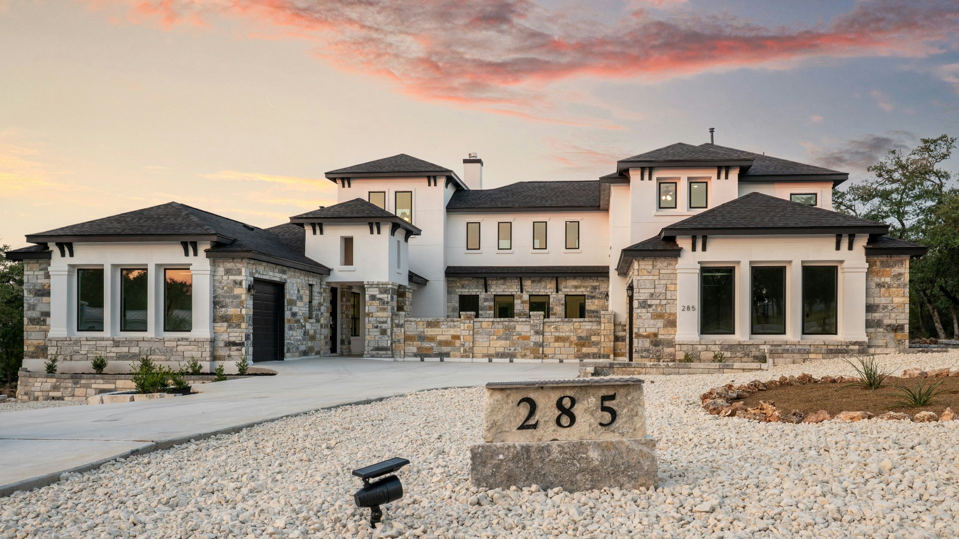 Modern luxury home with stone accents at sunset.