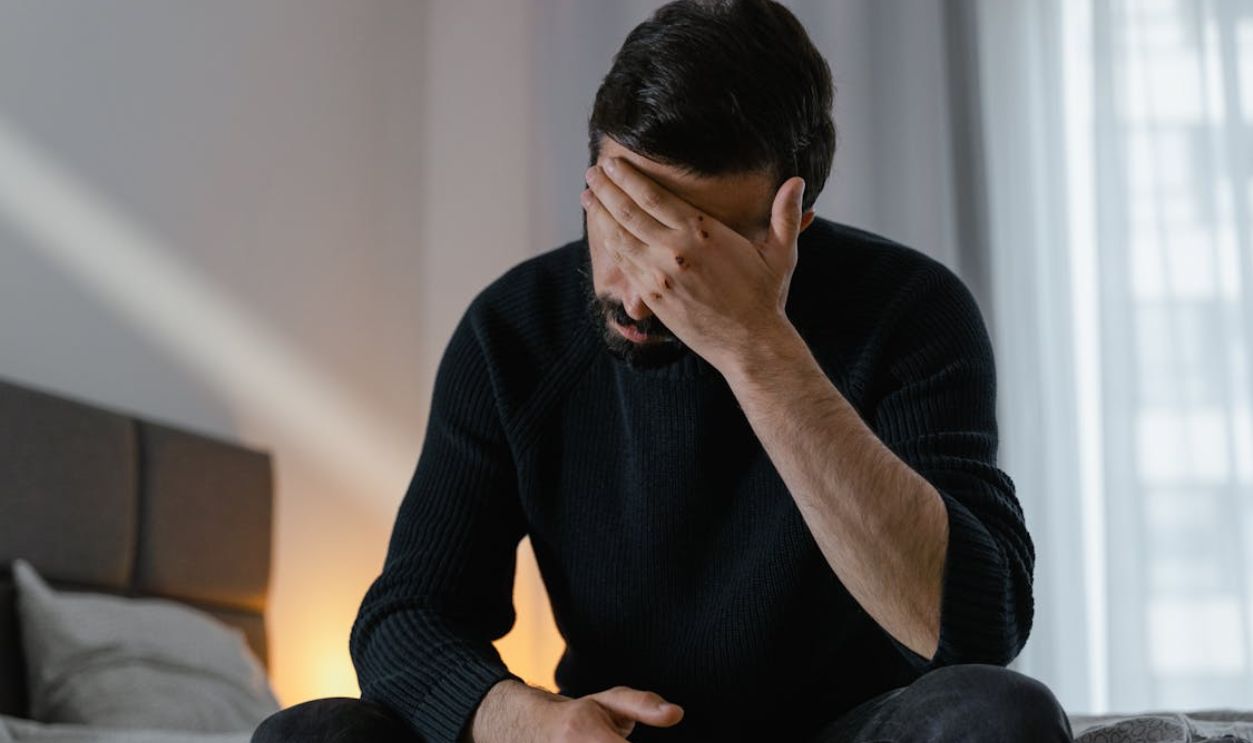 Man in Black Sweater Sitting on Bed