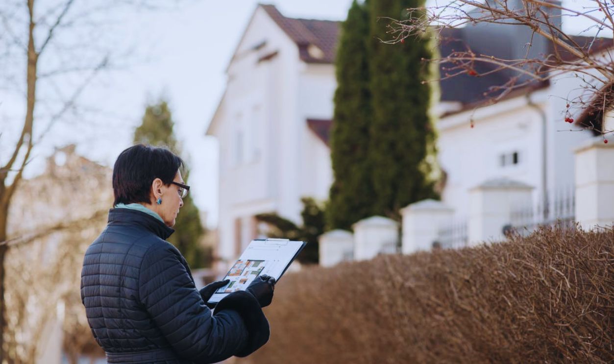 A Woman Standing on the Street while Holding a House Plan