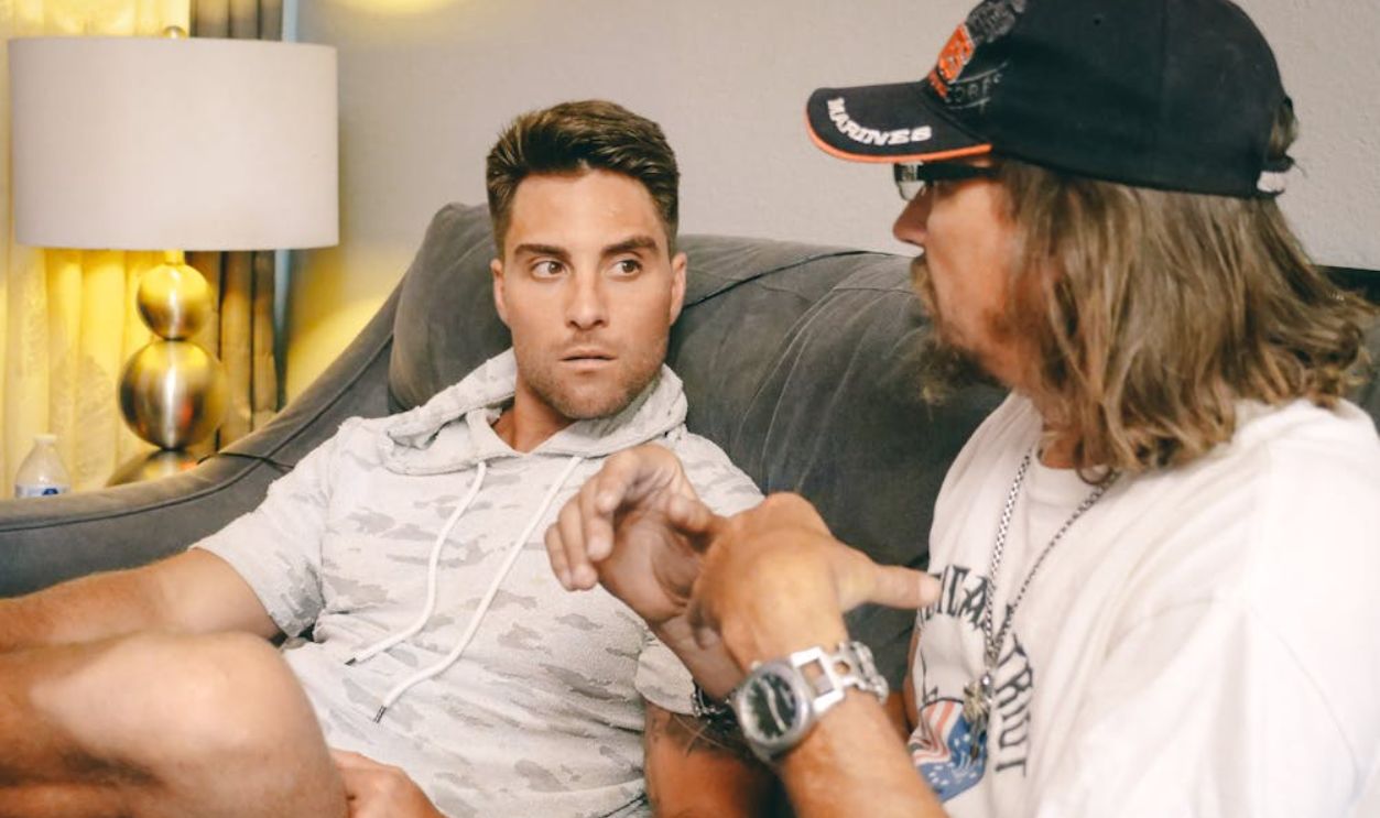 Two Men Sitting on Gray Sofa Having a Conversation