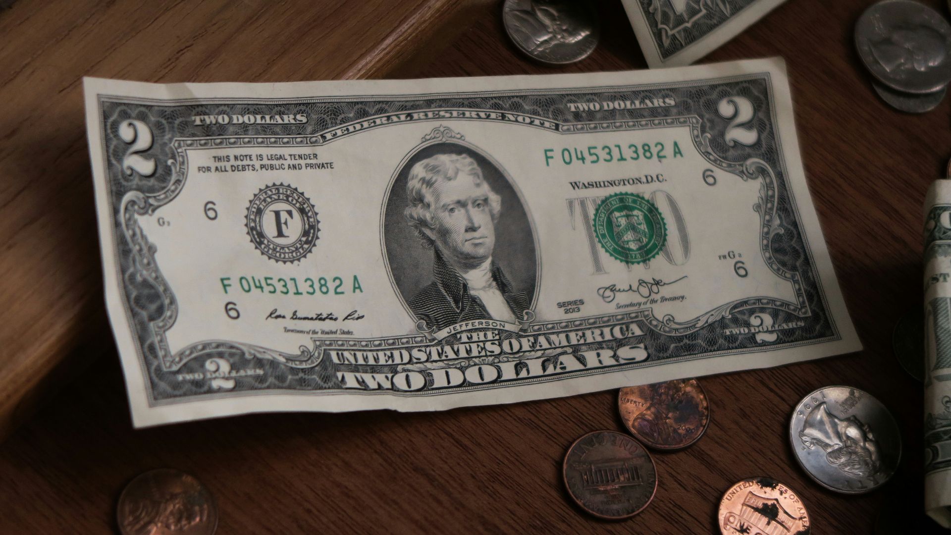 a roll of one hundred dollars sitting on top of a wooden table