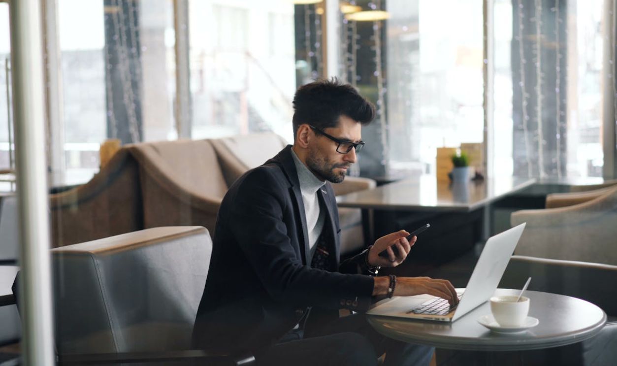 A man in a suit sitting at a table with a laptop
