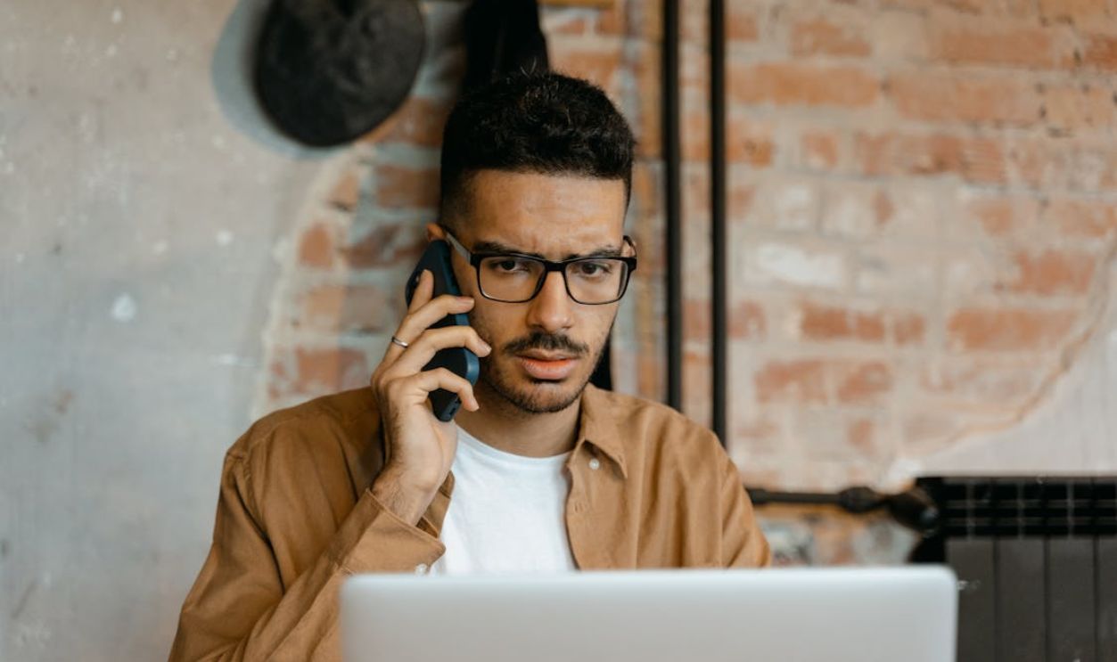 A Man in Brown Long Sleeves Wearing Eyeglasses while Talking on the Phone