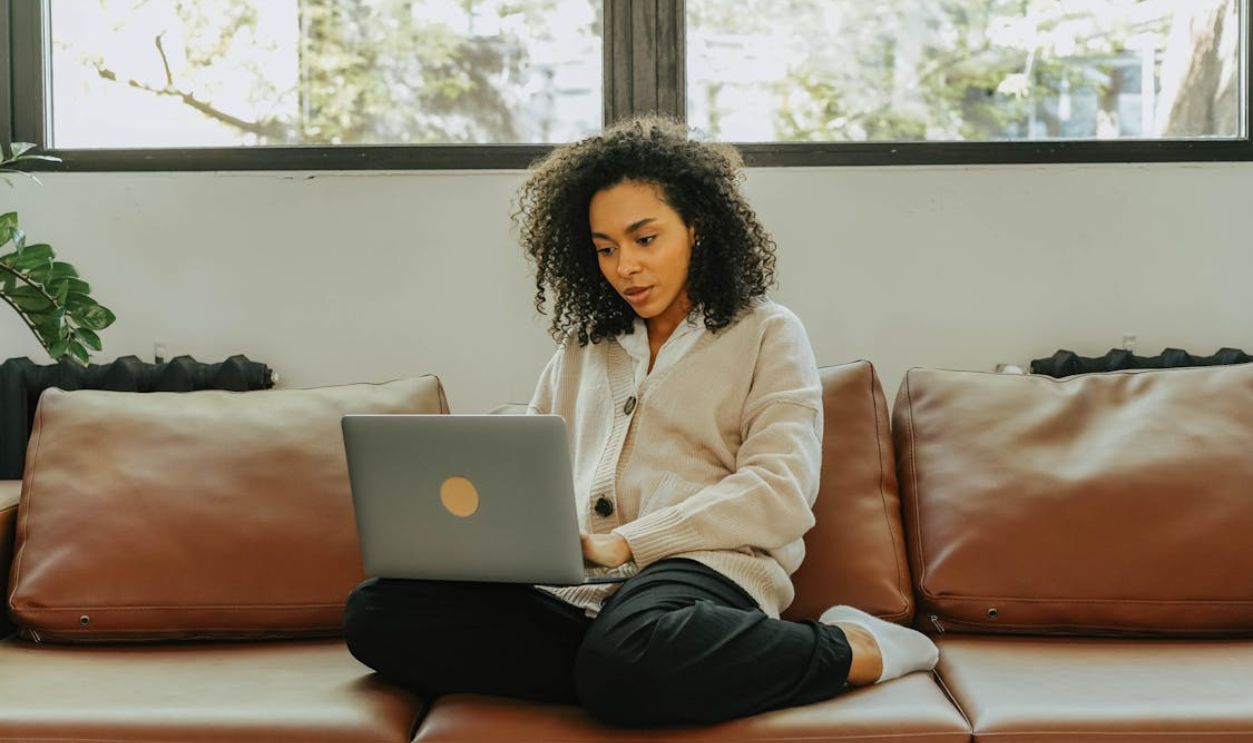 Woman in White Jacket Sitting on Couch Using Macbook