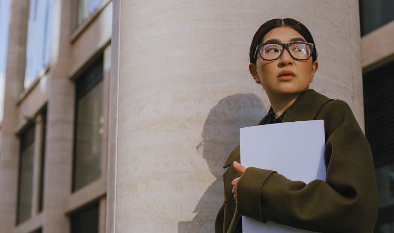 A Woman in Eyeglasses Wearing Coat While Holding Documents