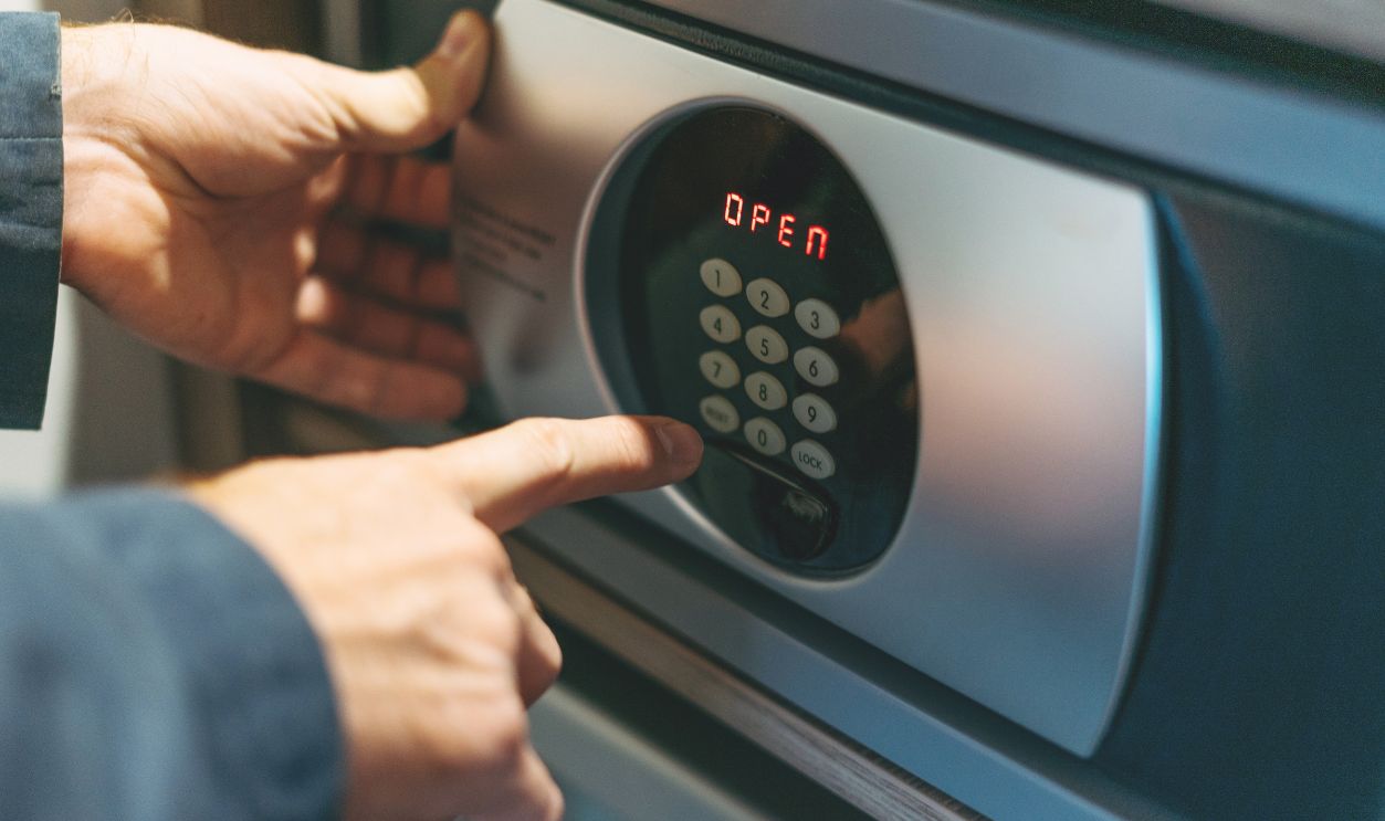 Adult man in blue jacket uses safe in hotel room