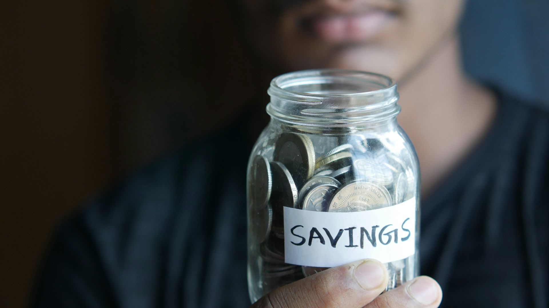 a man holding a jar with a savings label on it