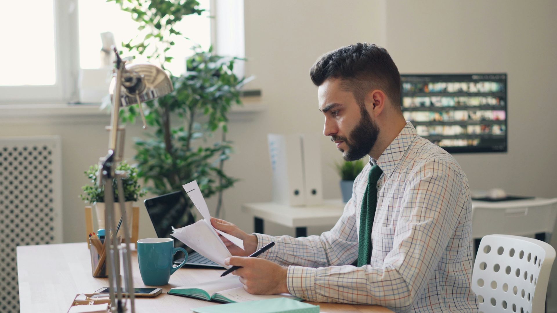 a man sitting at a desk with a laptop and papers