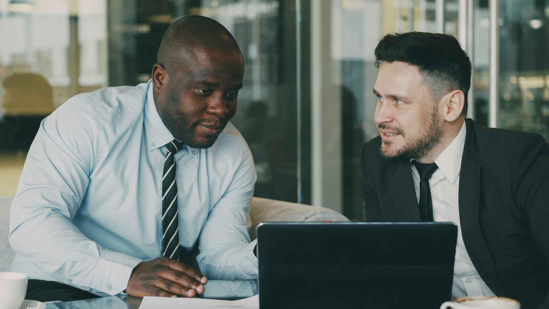 Two businessmen discussing documents at a table.