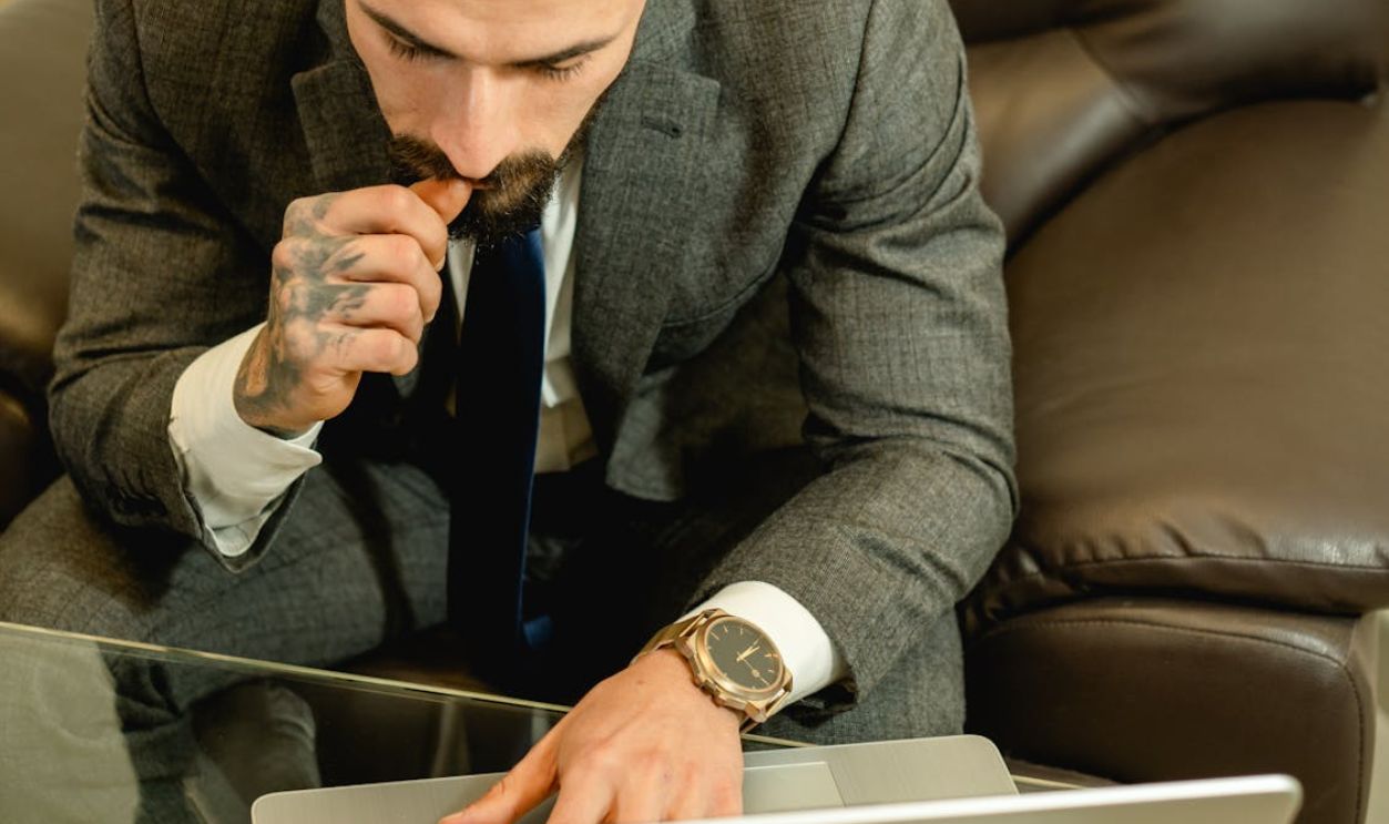 A Man in Gray Suit Jacket Sitting on a Leather Couch