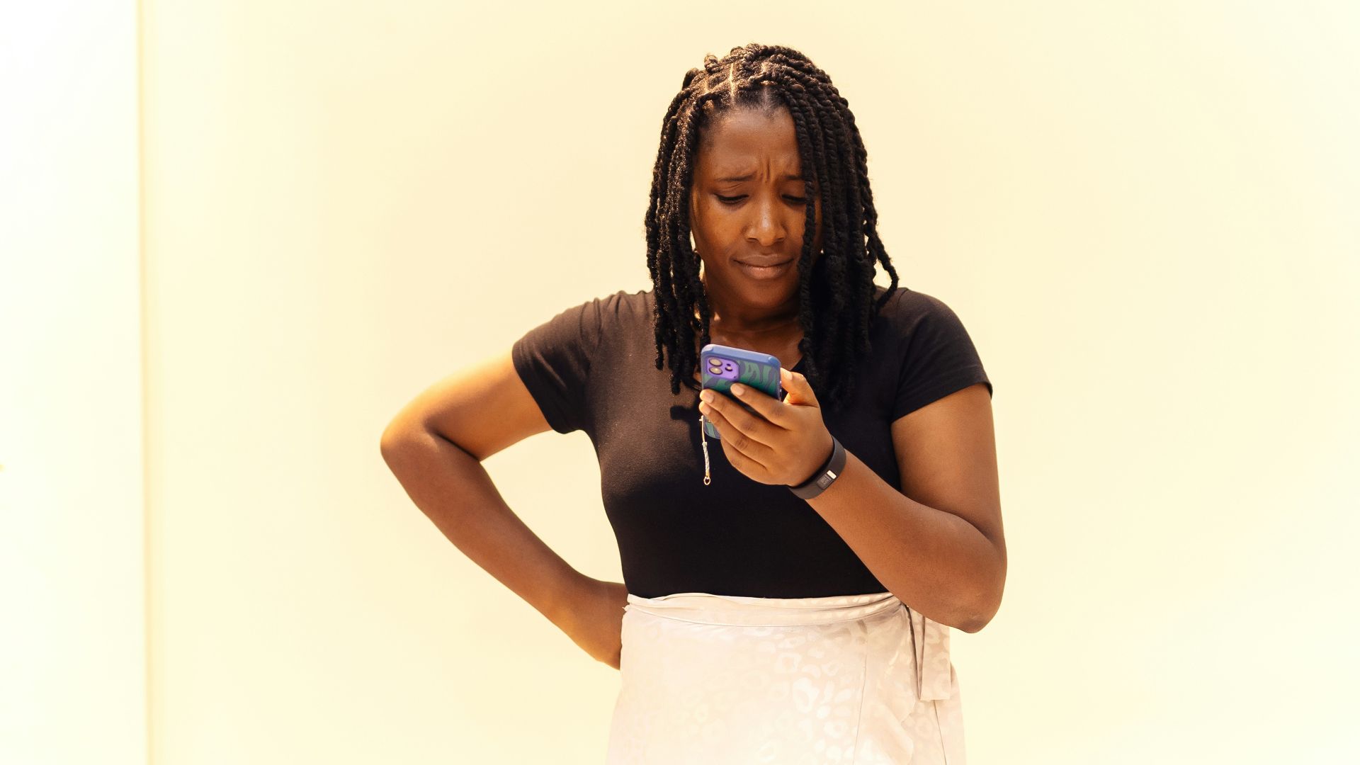 A woman standing in a room looking at her cell phone