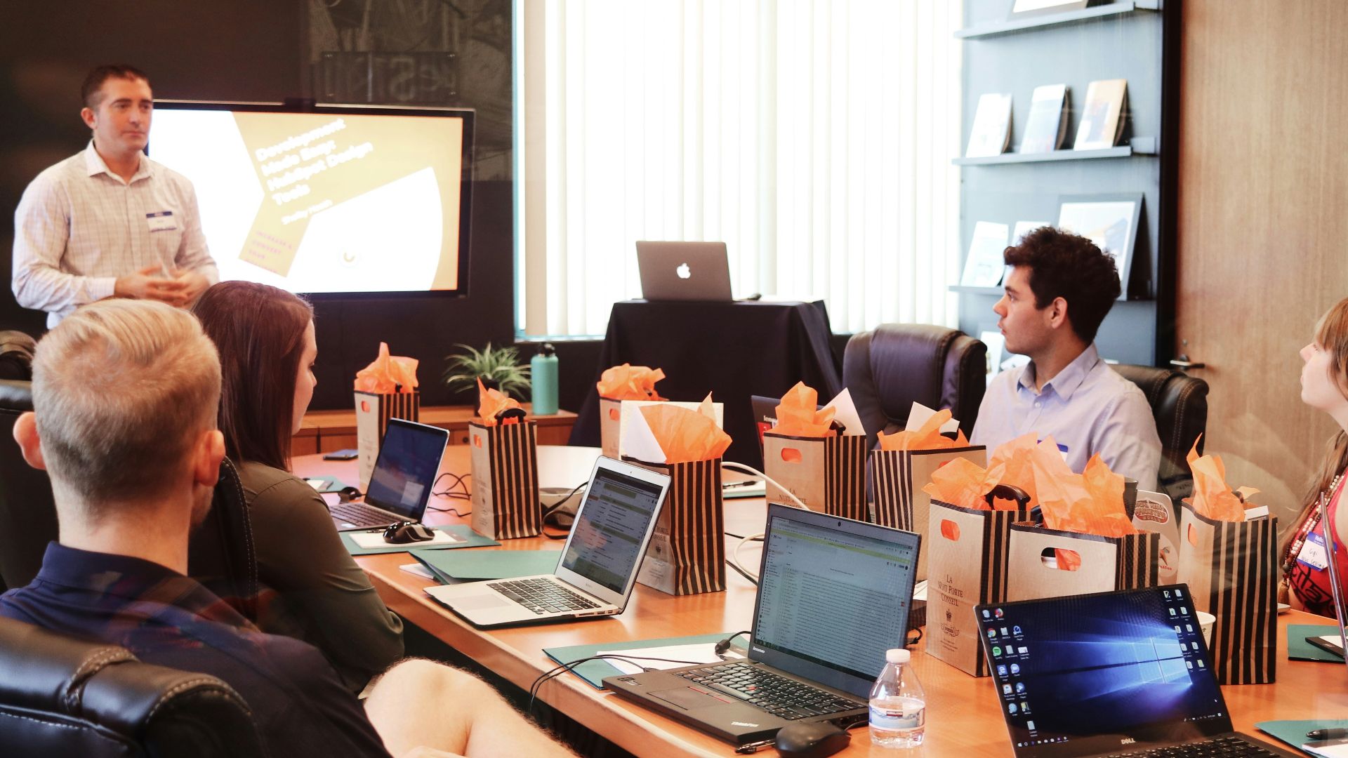 man standing in front of people sitting beside table with laptop computers