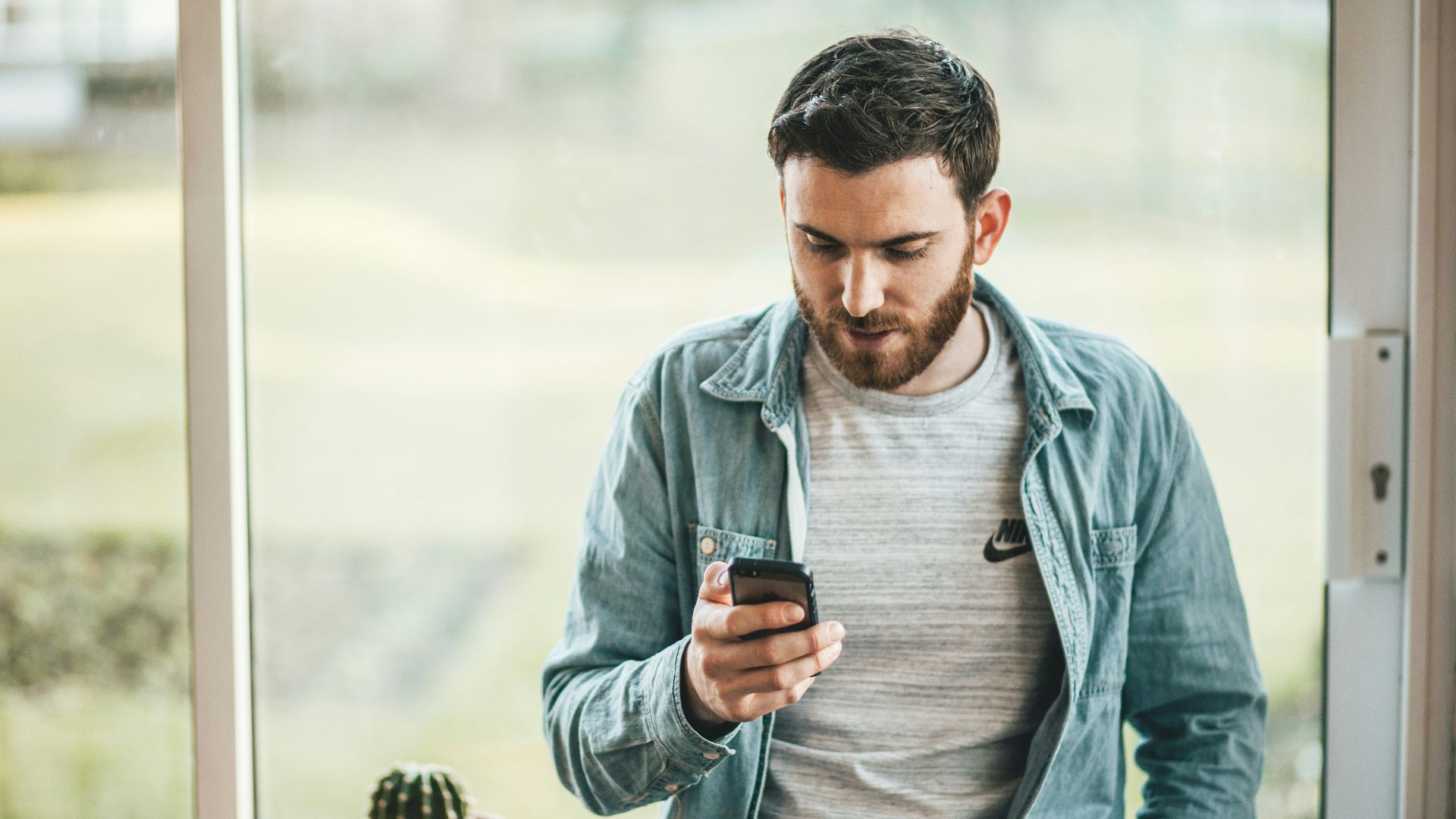 man holding a smartphone near the window
