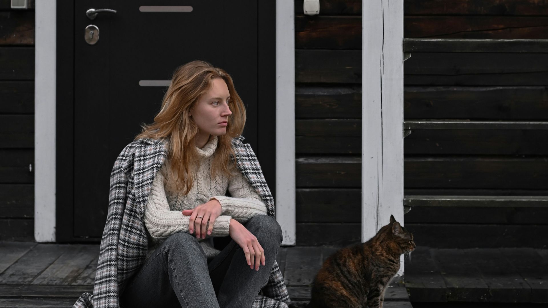 a woman sitting on a porch with a cat
