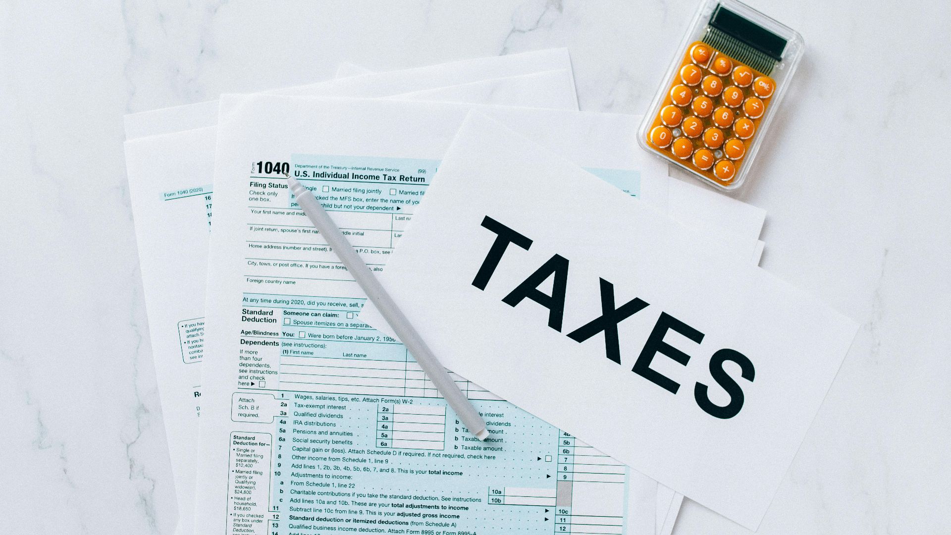 Top view of tax forms, a calculator, and pen for tax preparation.