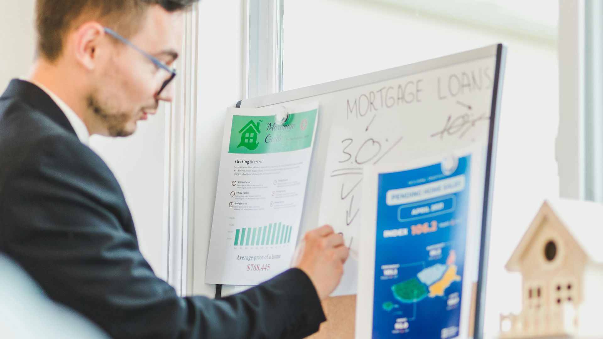 Real estate agent analyzing mortgage loan details on a whiteboard in an office setting.