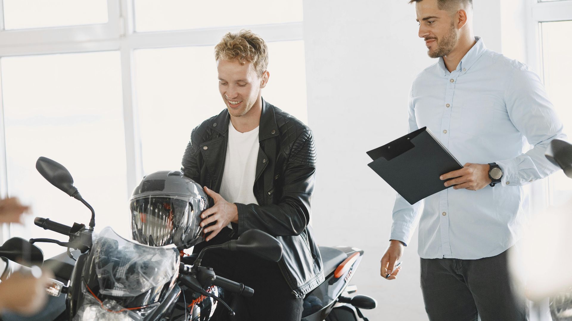 Two men at a motorcycle dealership discussing a motorbike purchase.