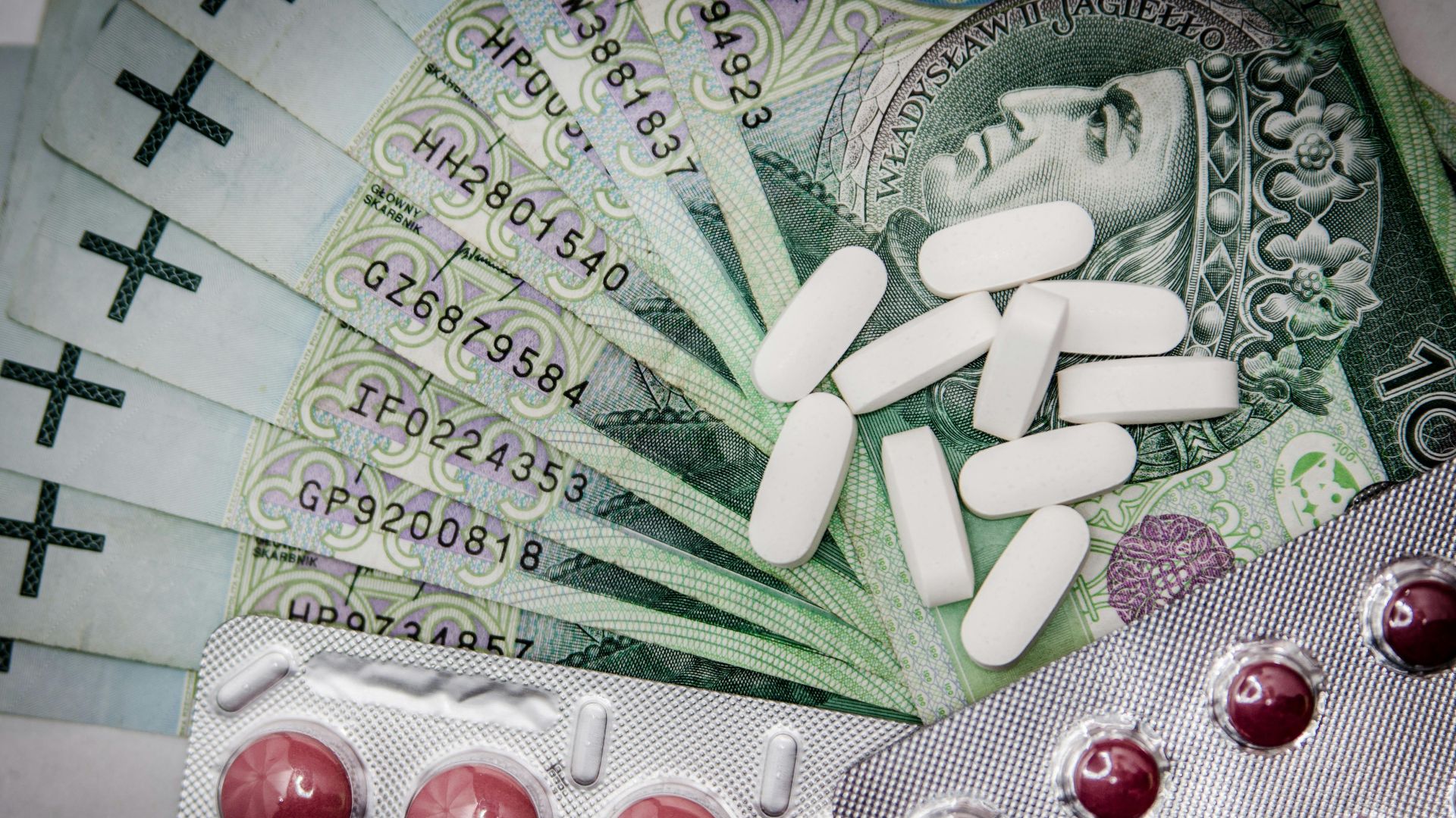 Polish 100 złoty notes with pills and blister packs, illustrating medical costs.