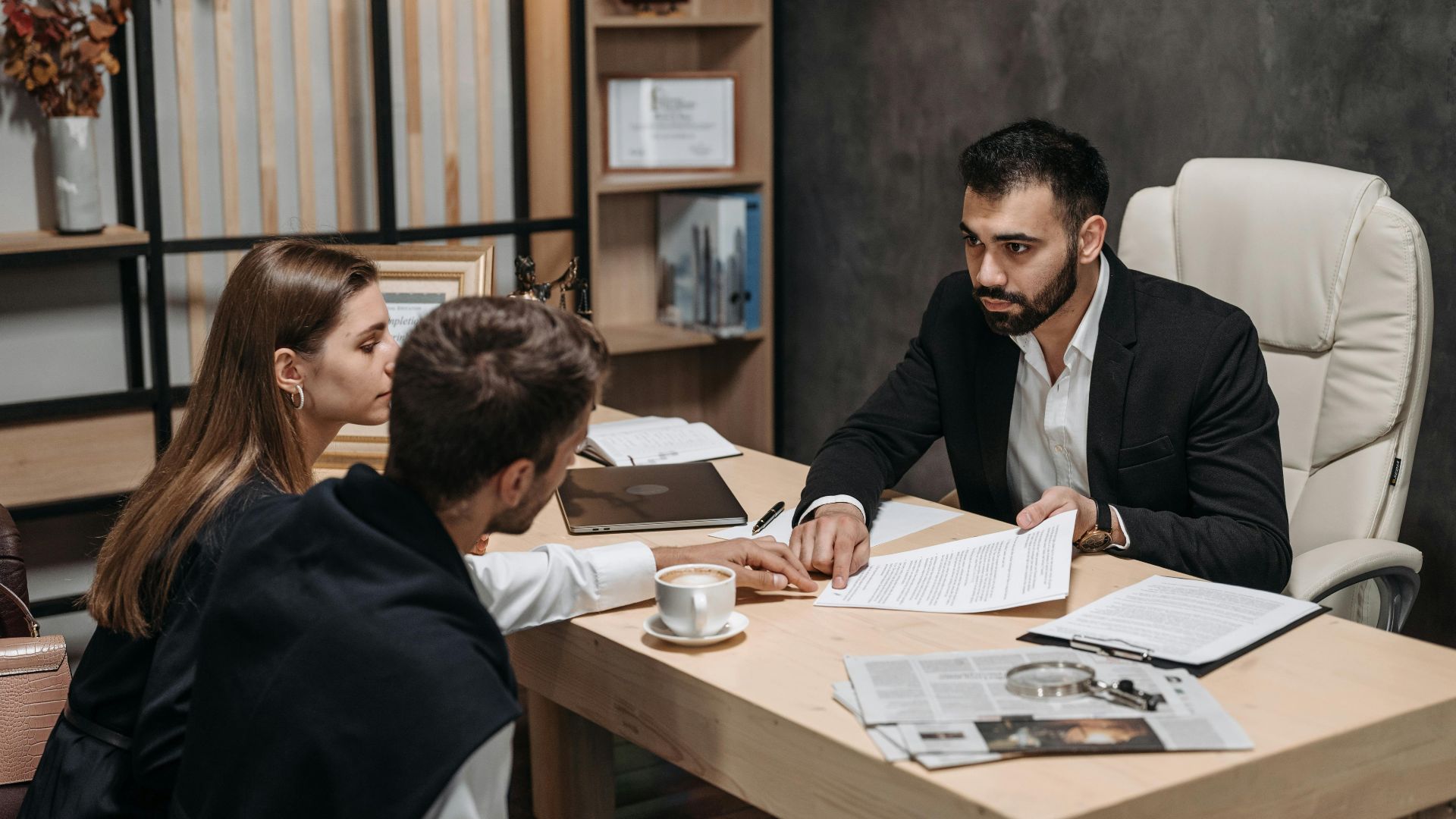 Lawyer discussing legal documents with clients at office desk.