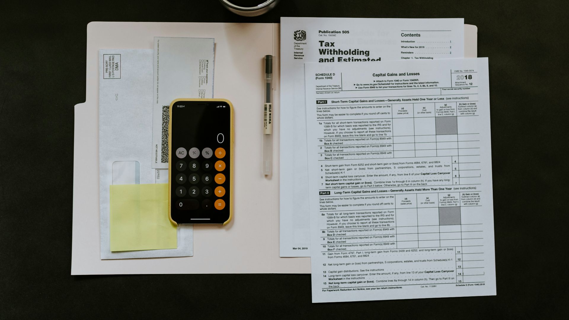 black Android smartphone near ballpoint pen, tax withholding certificate on top of white folder