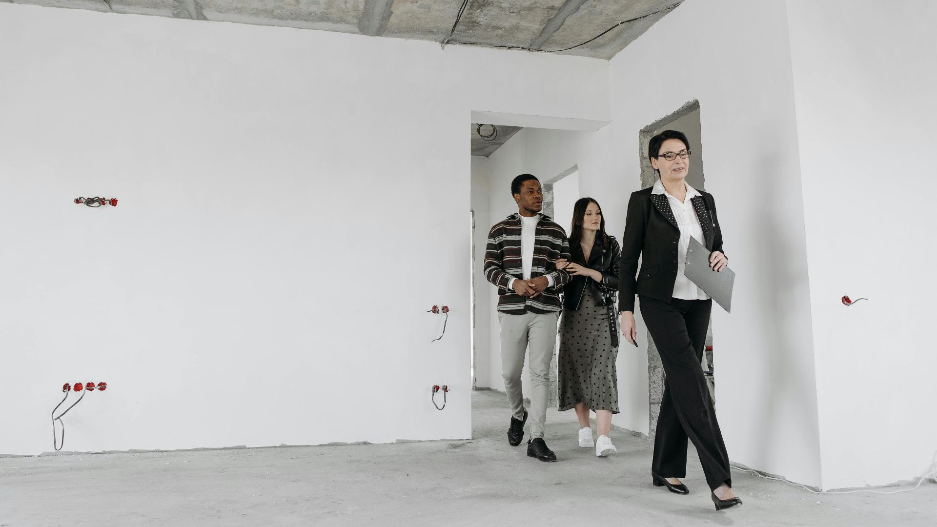 Real estate agent showing an unfinished house to potential buyers during a viewing session.
