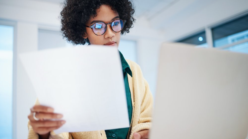 Female person or freelancer with paperwork on computer in financial plan
