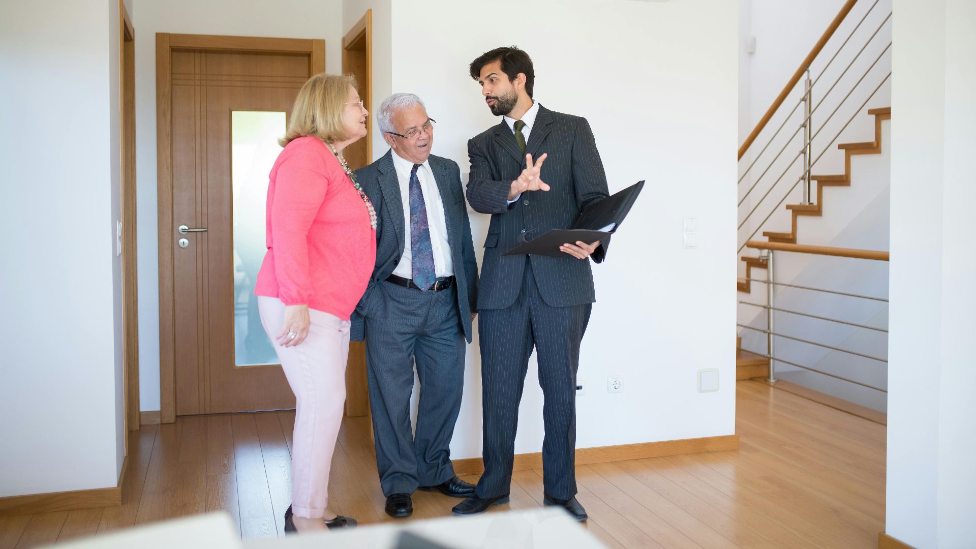 Realtor showing property to senior couple inside a modern home in Portugal.