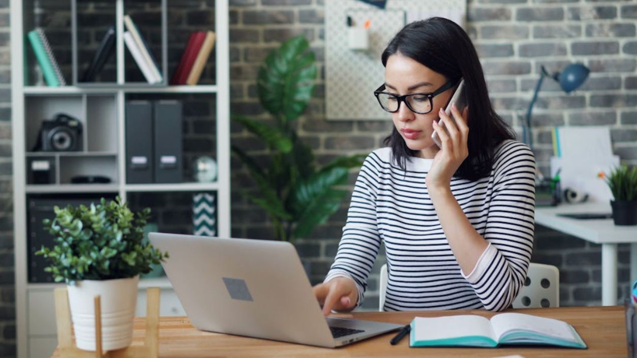 Office Worker Using a Laptop and Talking on the Phone