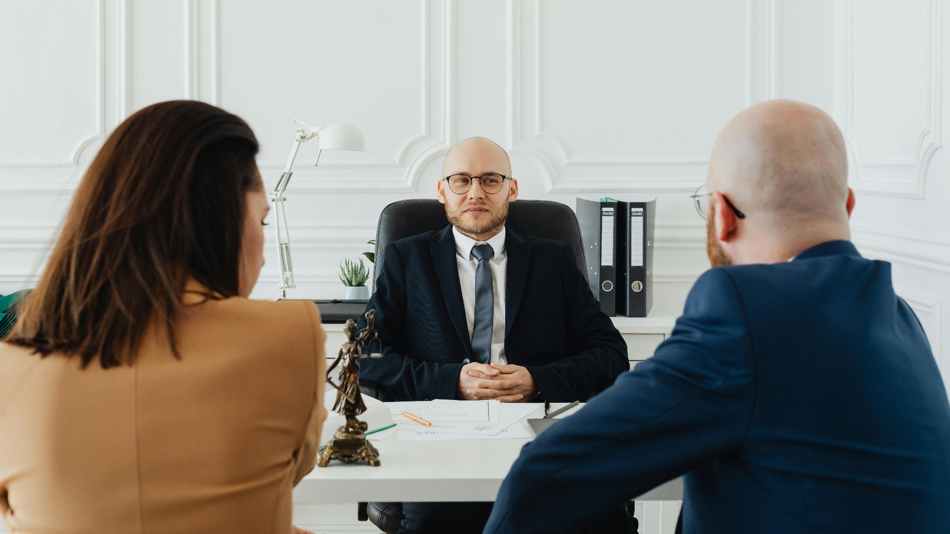 Lawyer meeting with clients in a formal office setting for legal consultation.