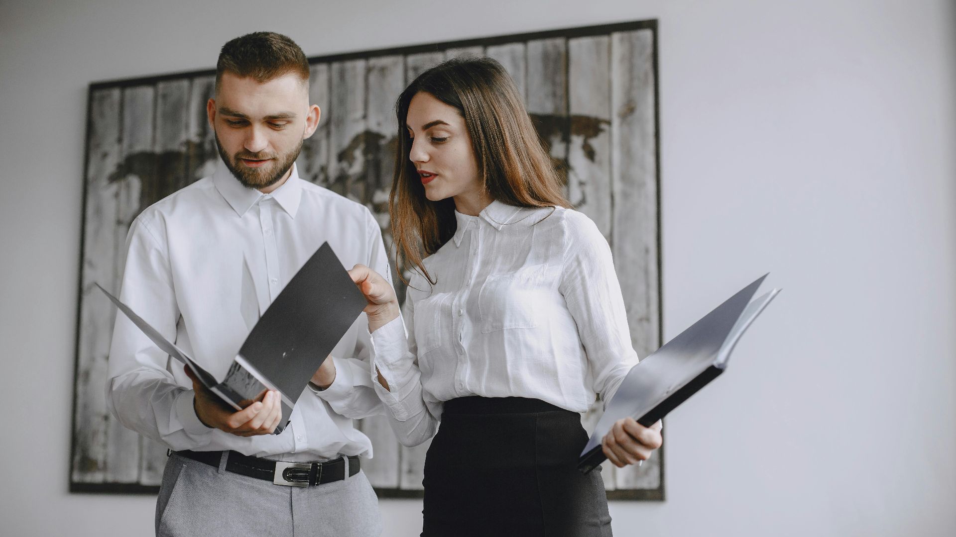 Two colleagues in a modern office reviewing documents together.