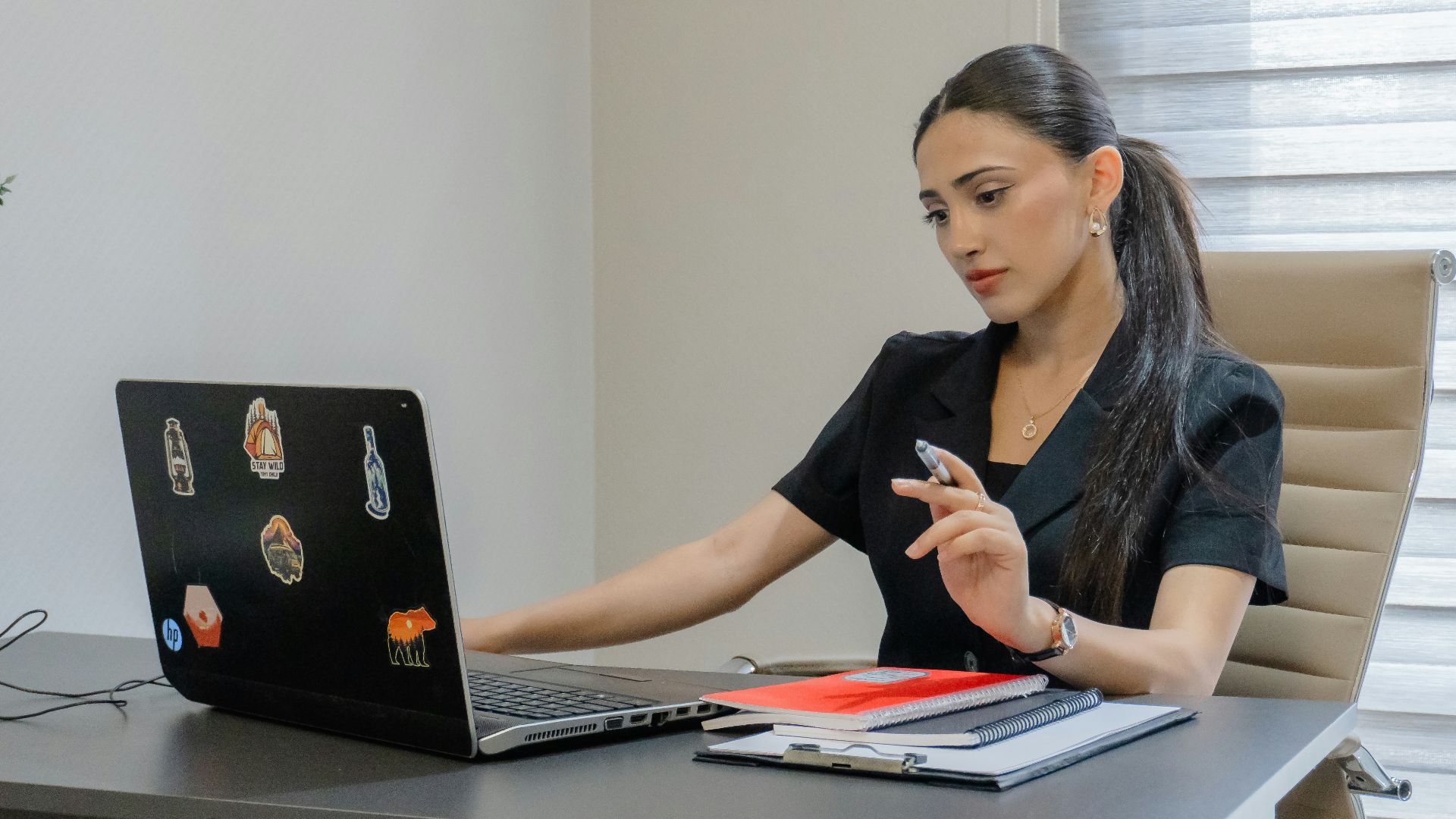A woman working on a laptop at a desk.