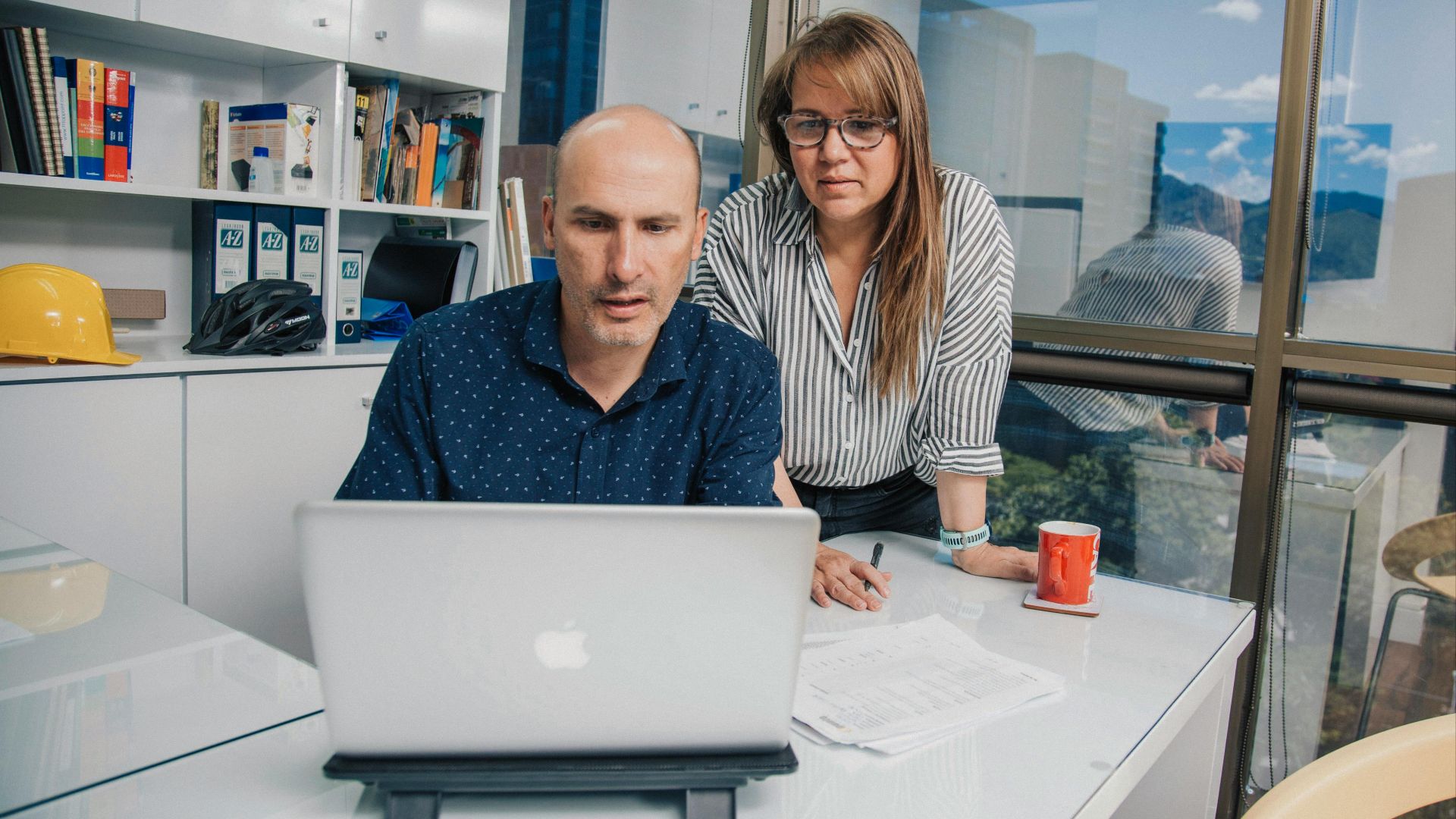 Colleagues collaborating at a desk in a modern office setting.