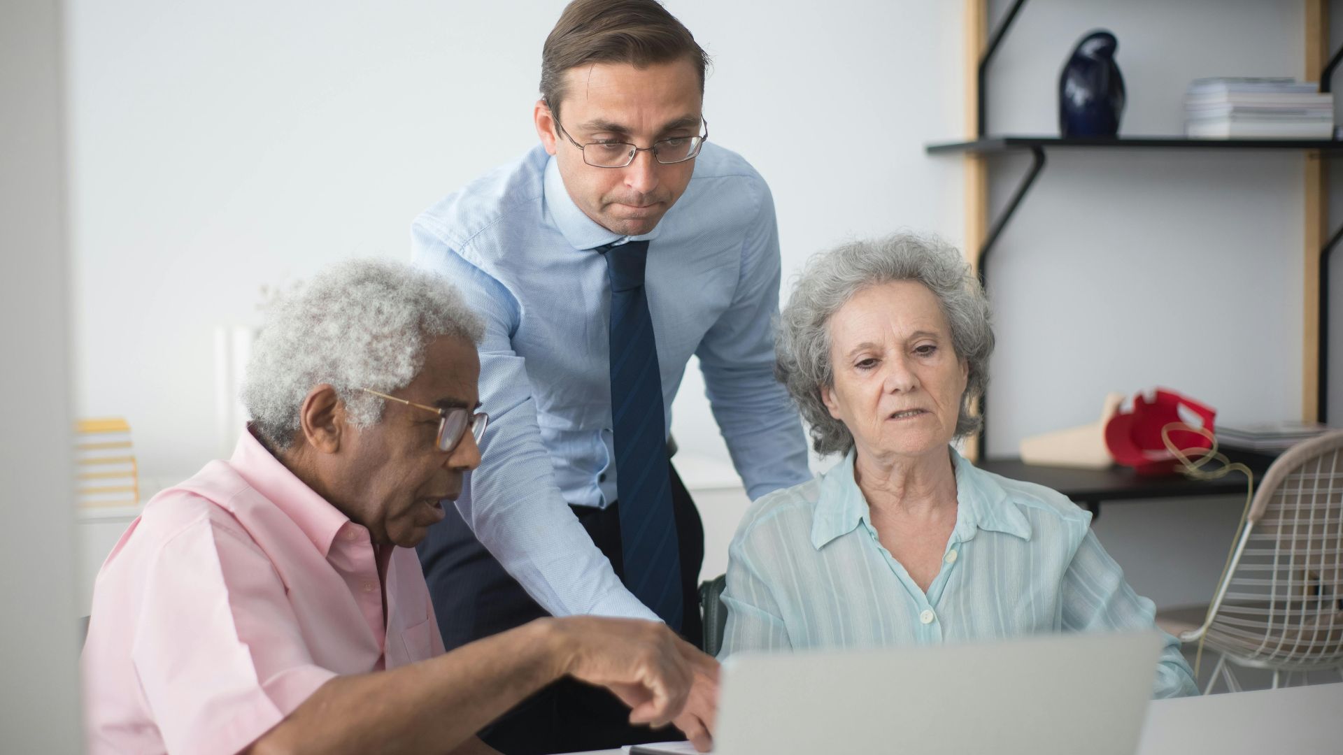 Senior couple consulting with a business agent at home on a laptop.
