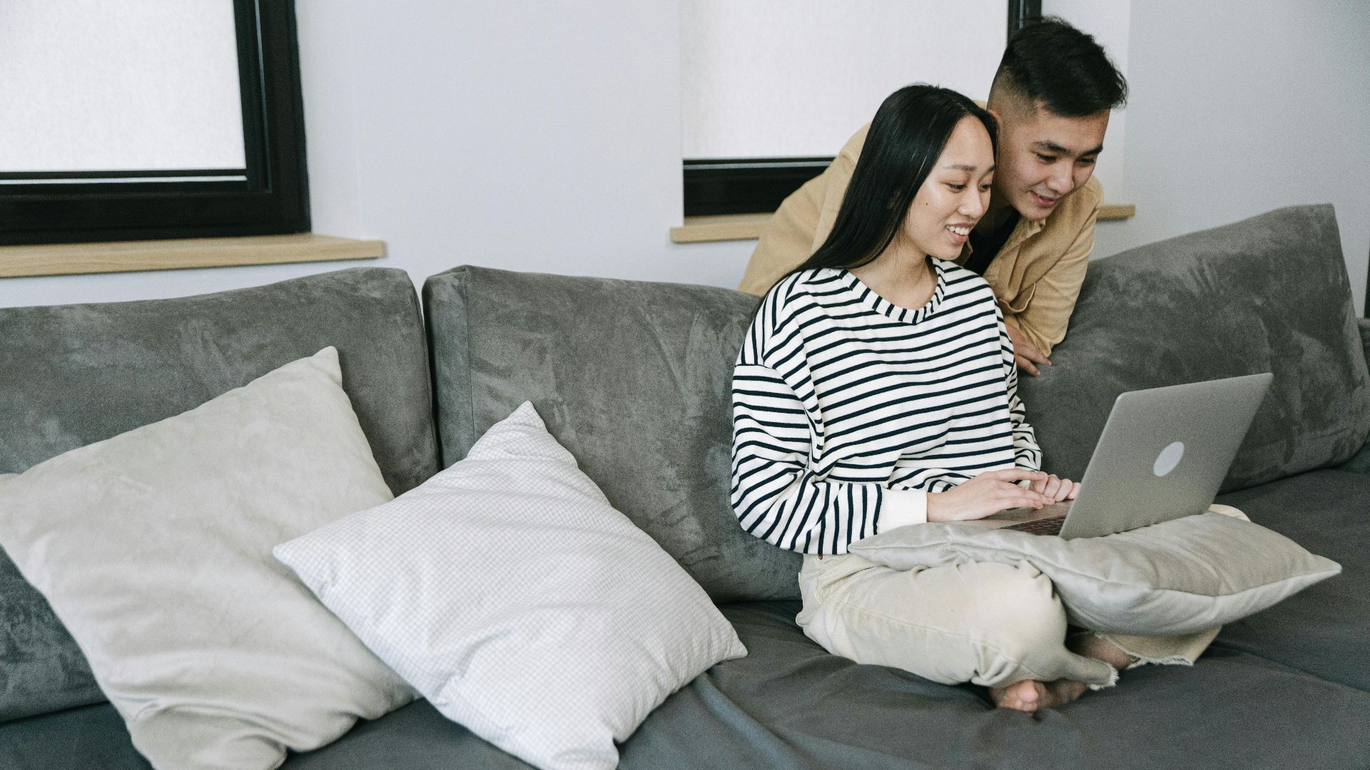 Young couple browsing on a laptop while sitting comfortably on a sofa at home.