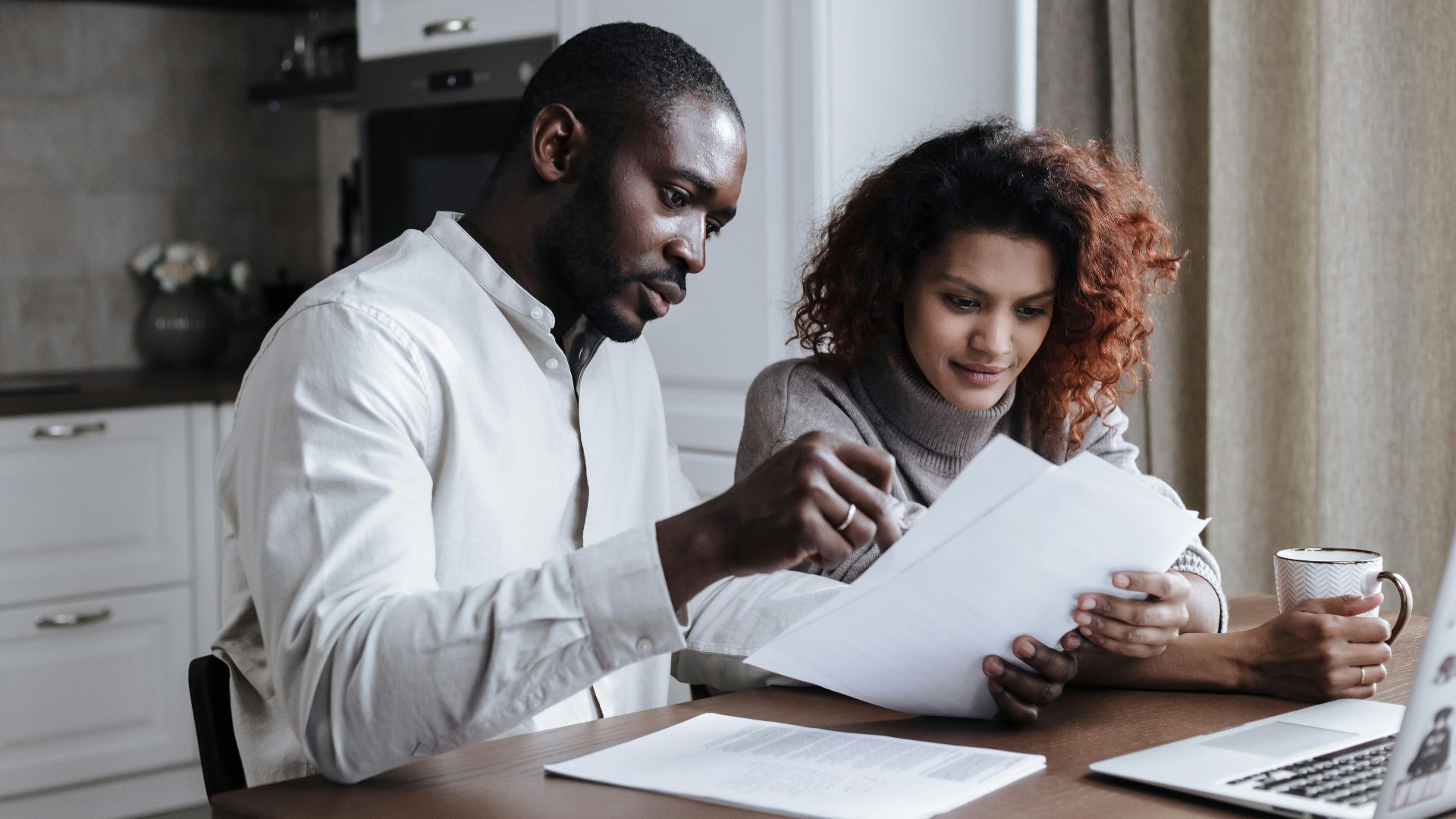Couple working together on documents at home interior using a laptop.