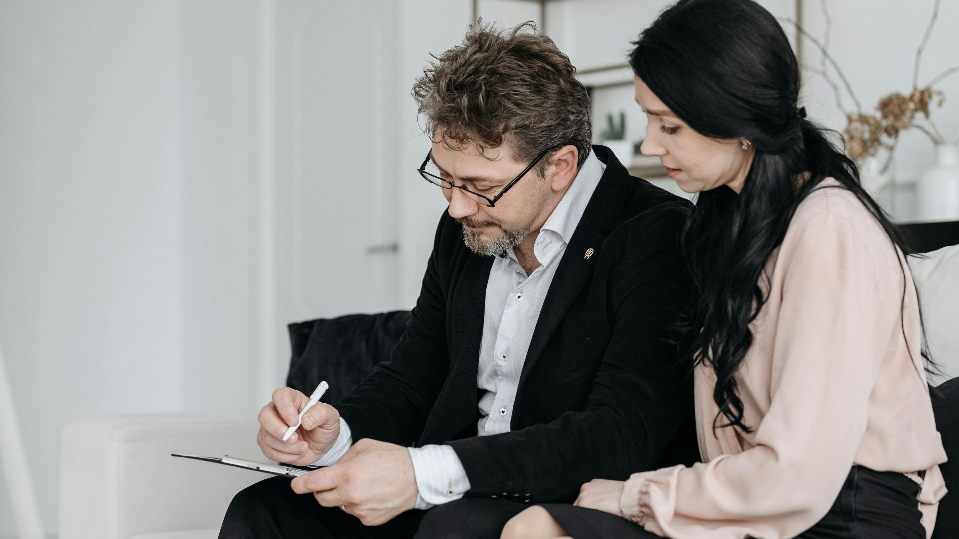 A business man and woman signing documents in a modern home interior.