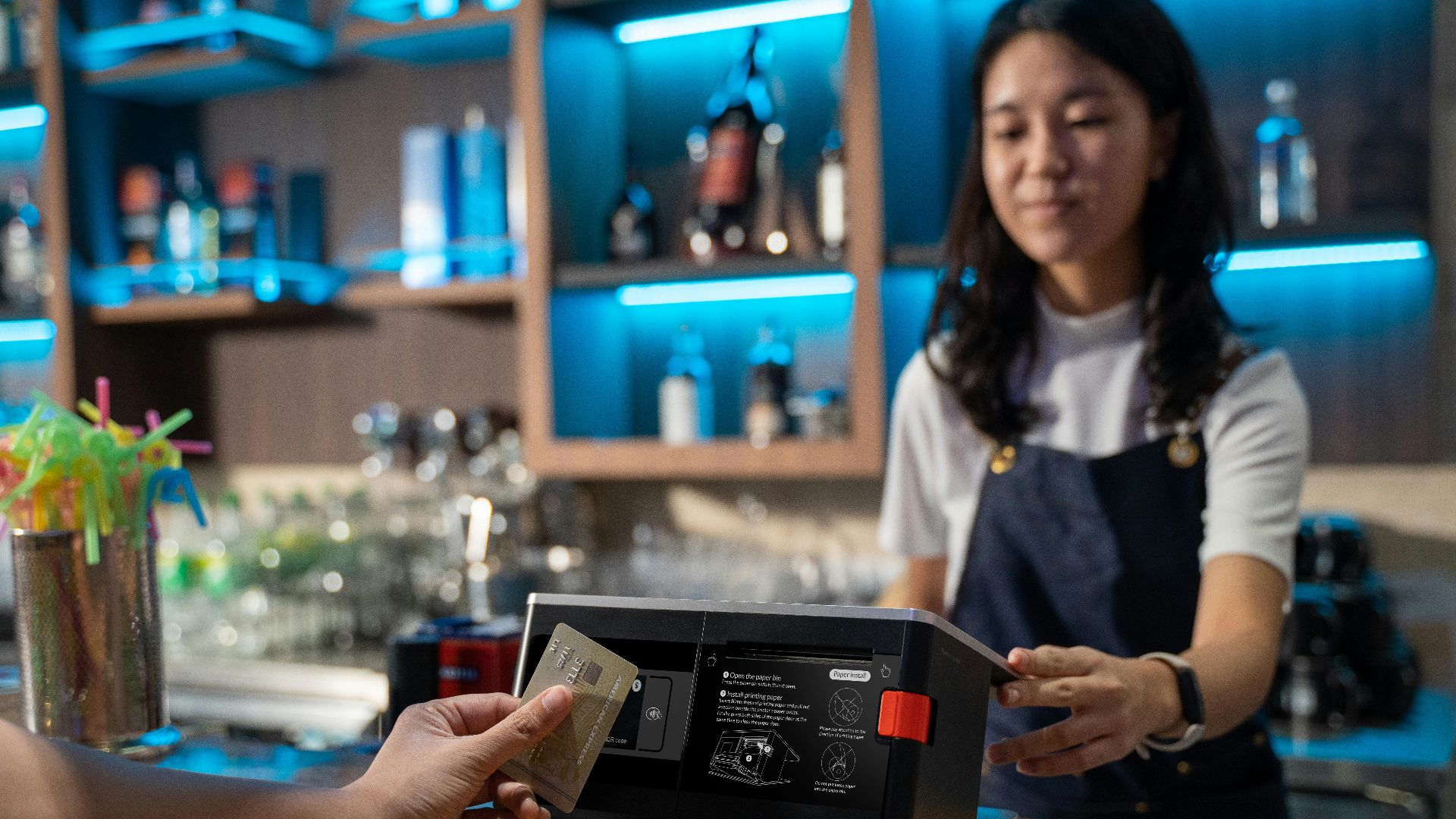 Customer making a cashless payment with a credit card at a bar, highlighting modern technology.