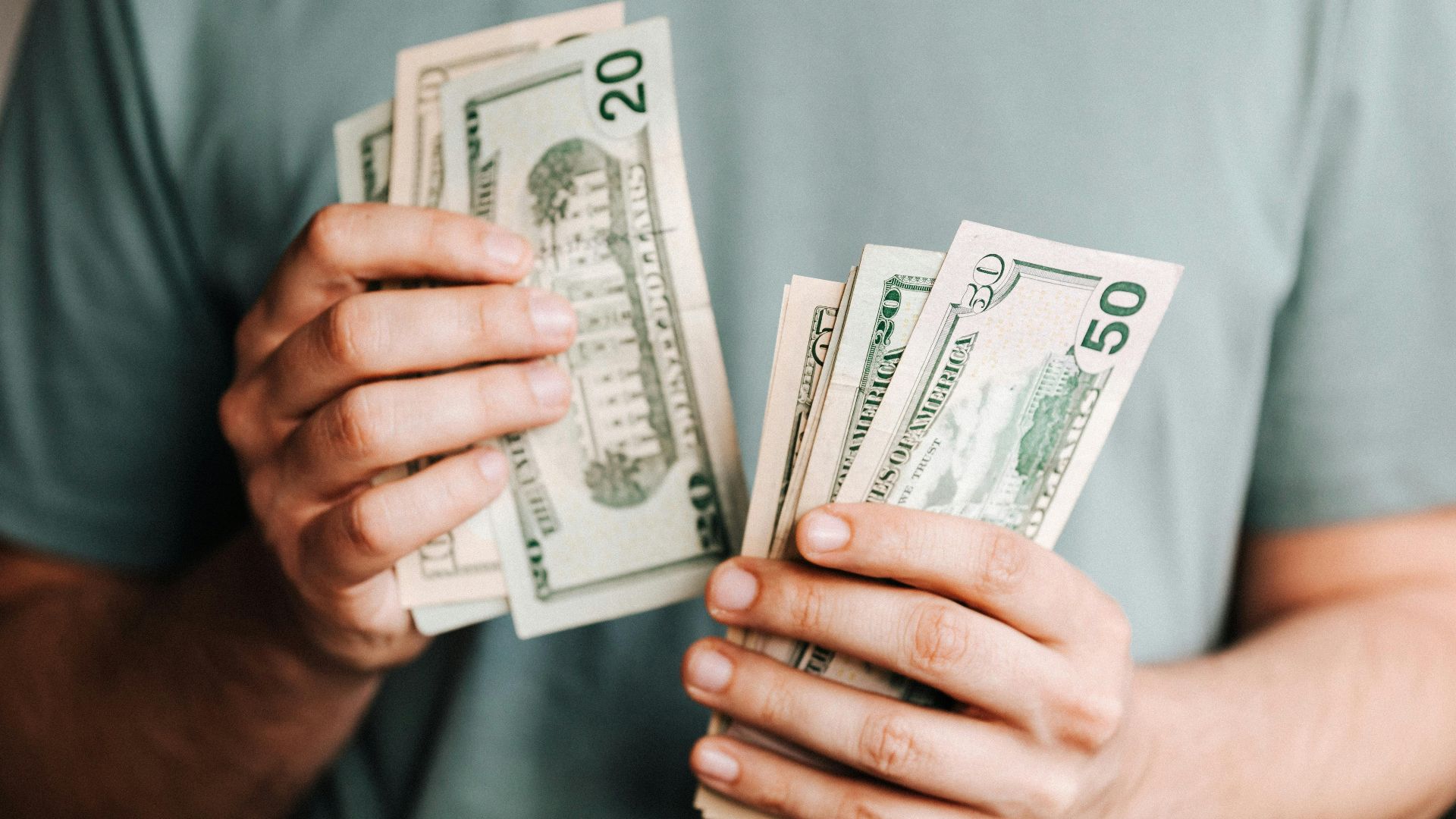Close-up of a person counting US dollar bills indoors. Financial concept.