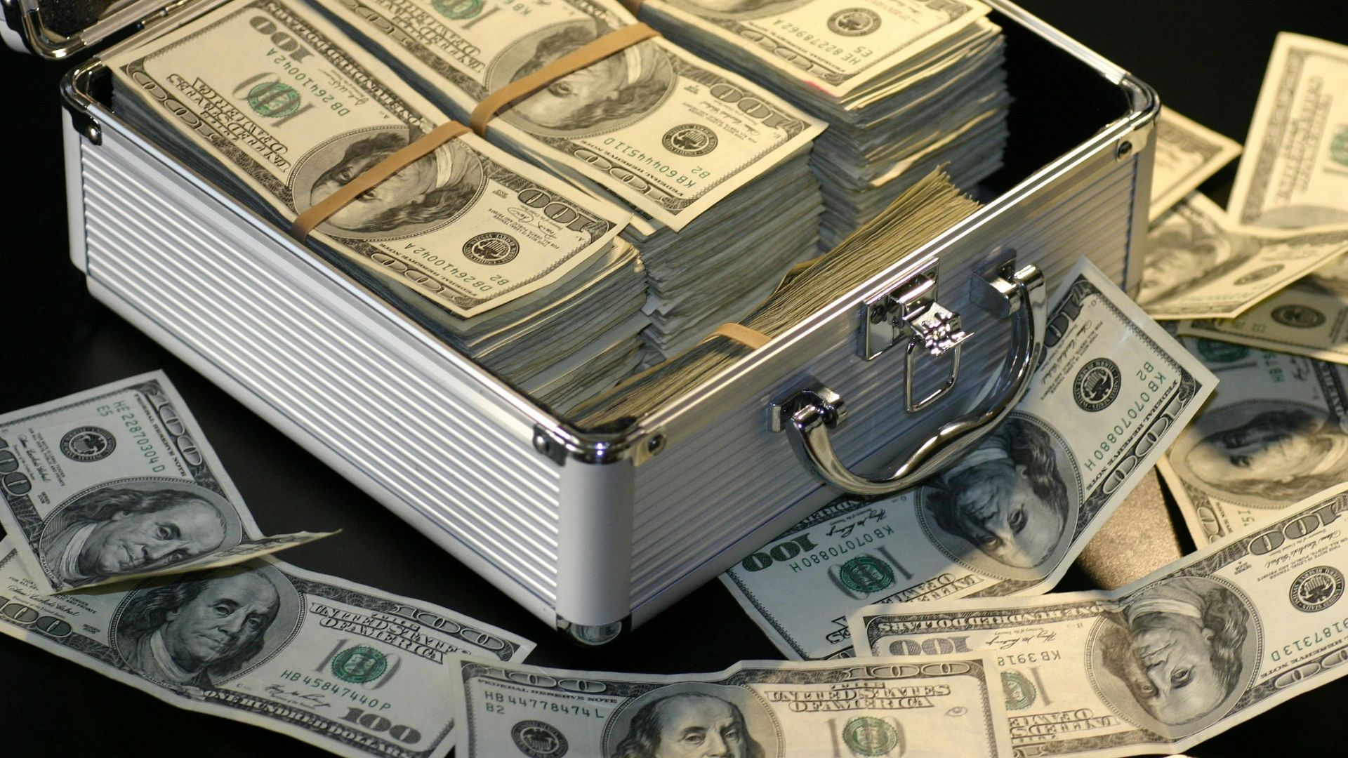 A metallic briefcase full of US dollar bills, symbolizing wealth and investment.