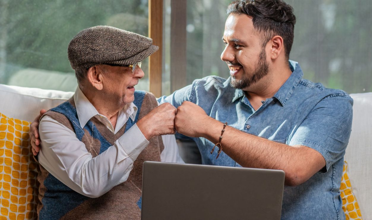 Happy adult senior father with his adult son. Young man enjoys teaching his older father how to use a laptop. How to use technology. 
