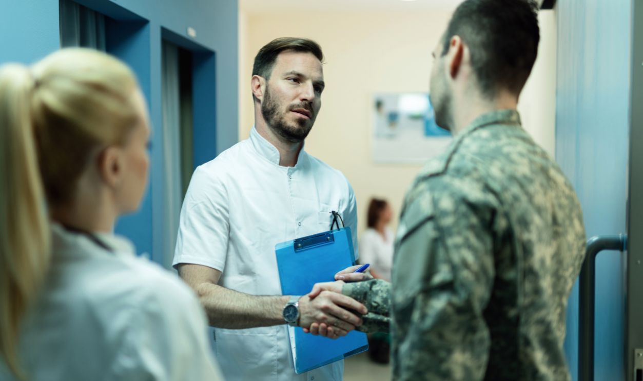 Army soldier handshaking with a doctor in a lobby at clinic. Focus is on doctor. 