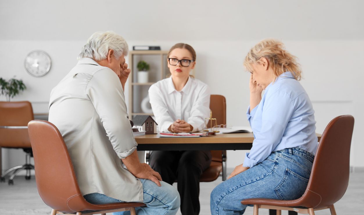 Female divorce lawyer working with mature couple at table in office