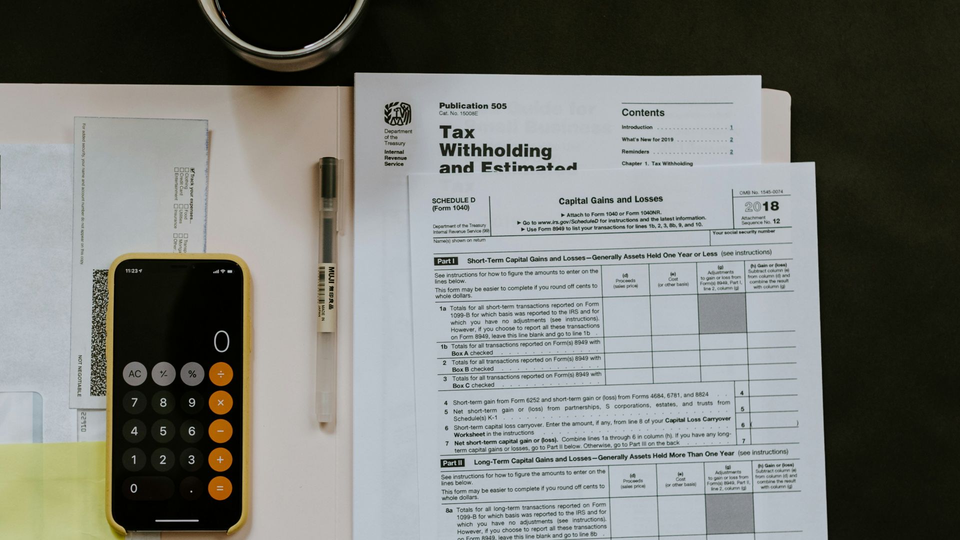 black Android smartphone near ballpoint pen, tax withholding certificate on top of white folder