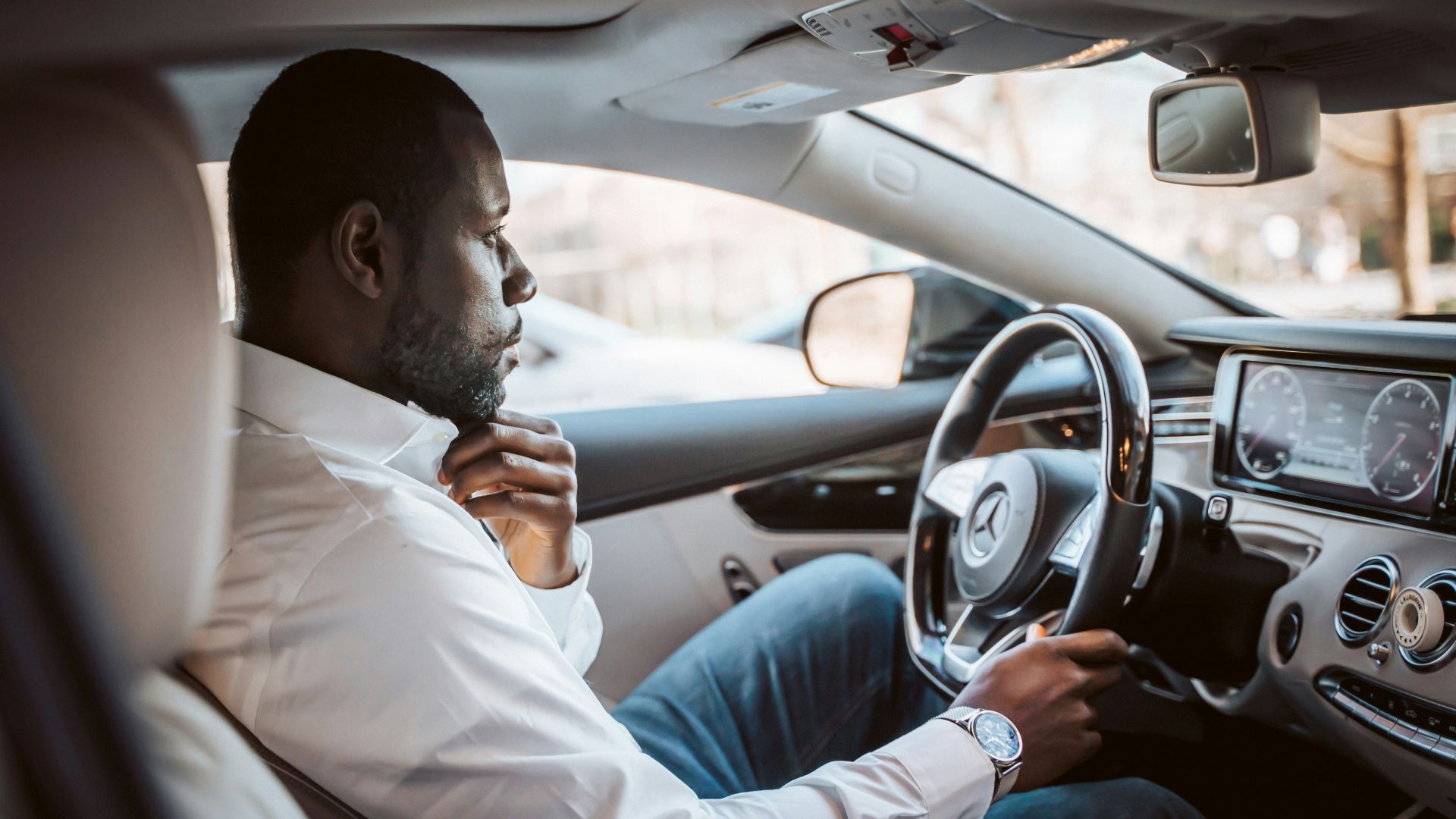 man in white dress shirt driving car during daytime