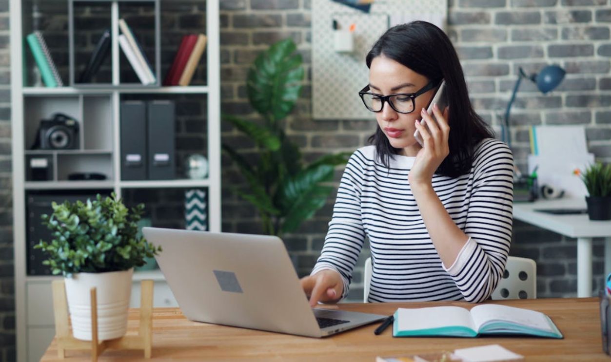 Office Worker Using a Laptop and Talking on the Phone
