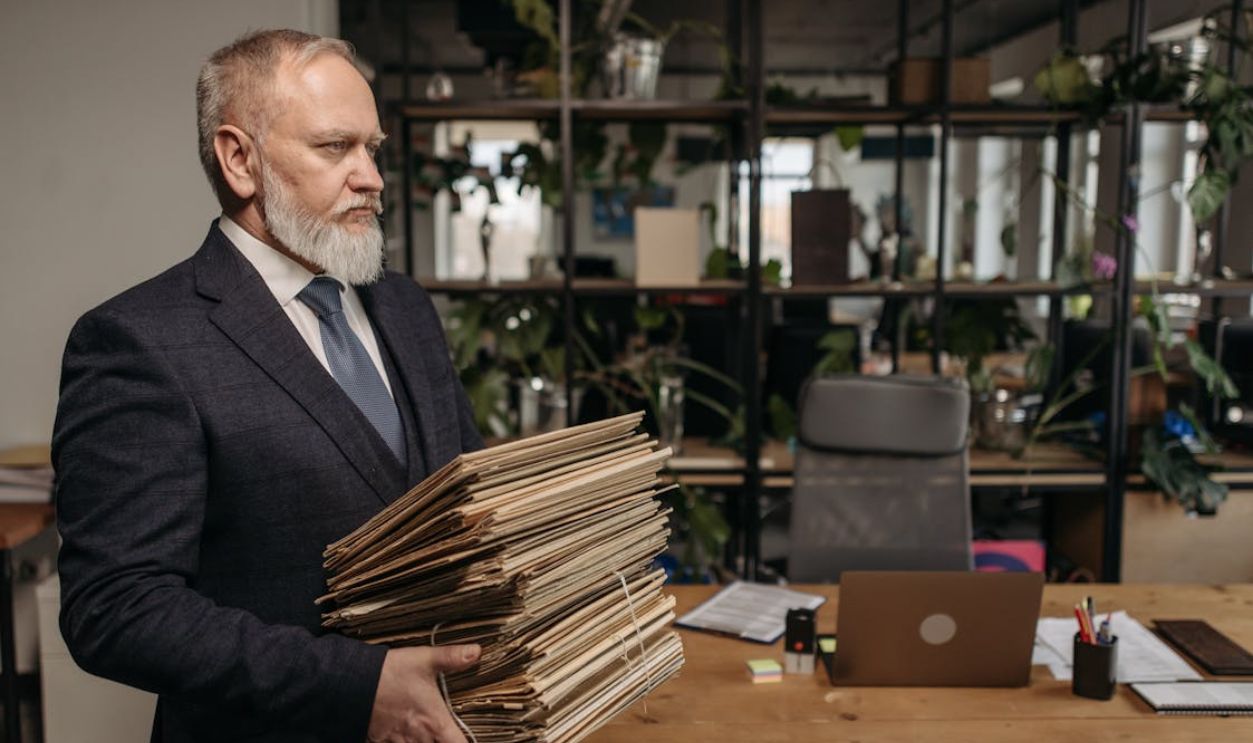 A Man in Black Suit Carrying a Pile of Documents in Envelopes