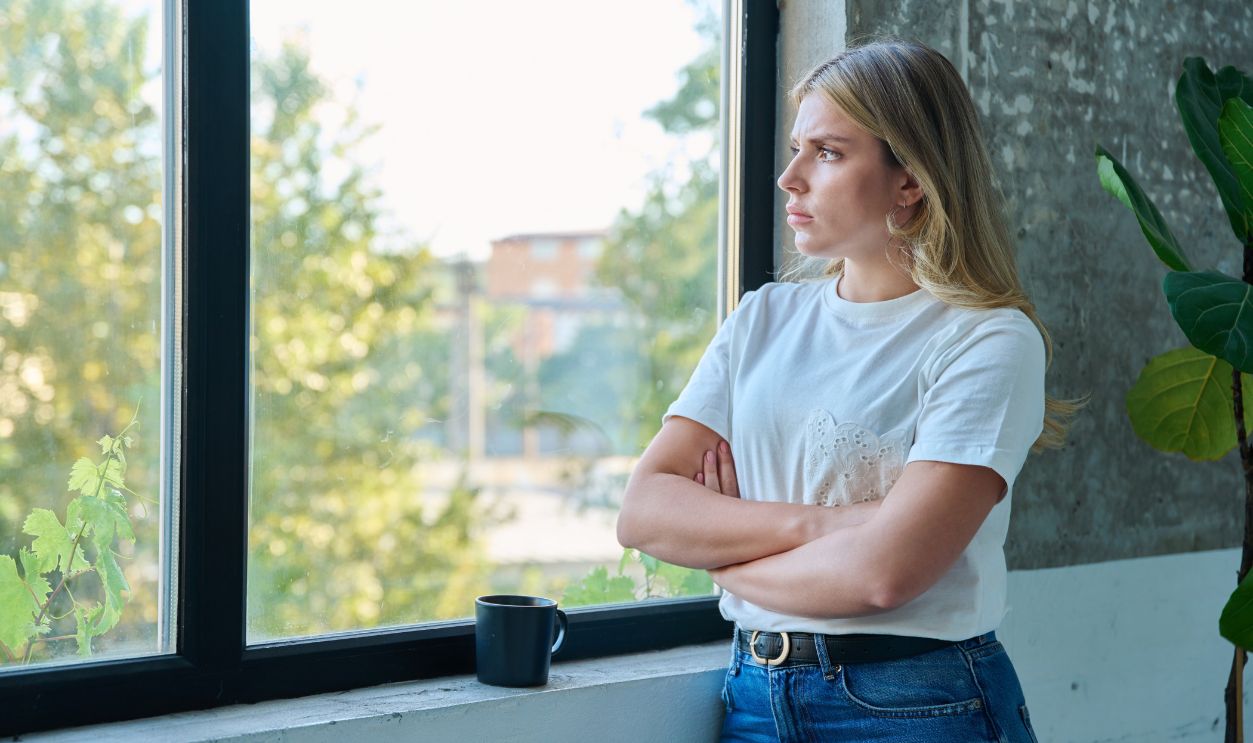 Sad unhappy young woman looking out the window, profile view, copy space