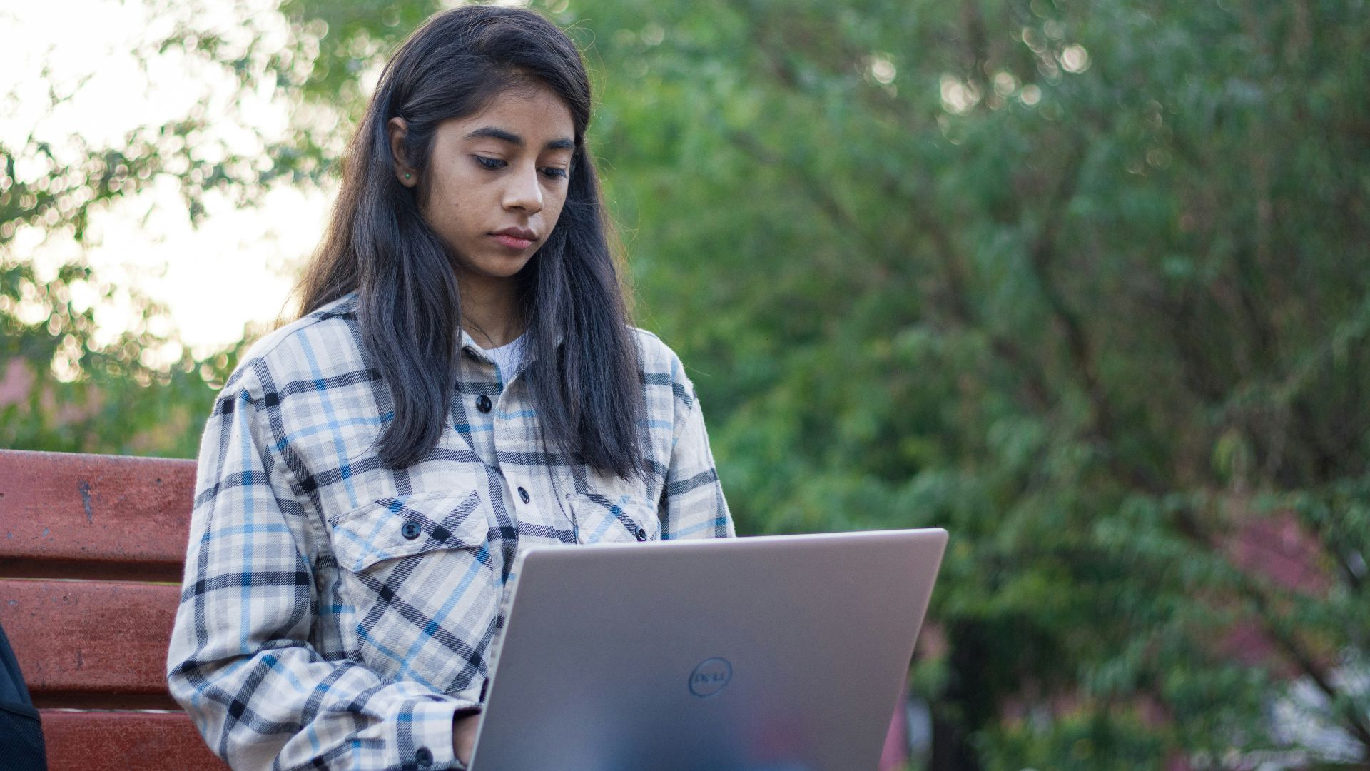 a woman sitting on a bench using a laptop computer