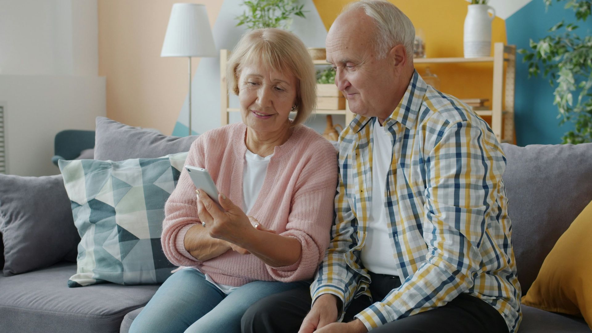 Elderly couple looking at a smartphone together on couch.