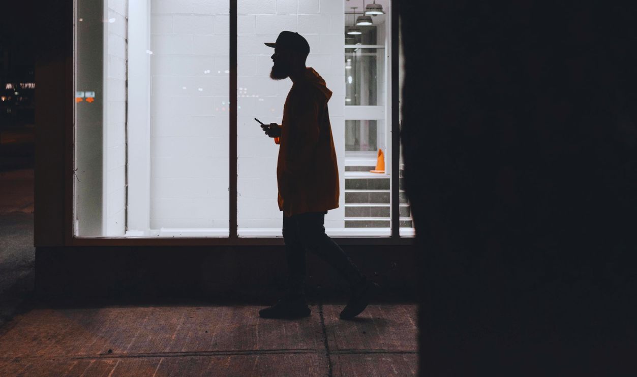 A Side View of a Man Walking on the Street at Night